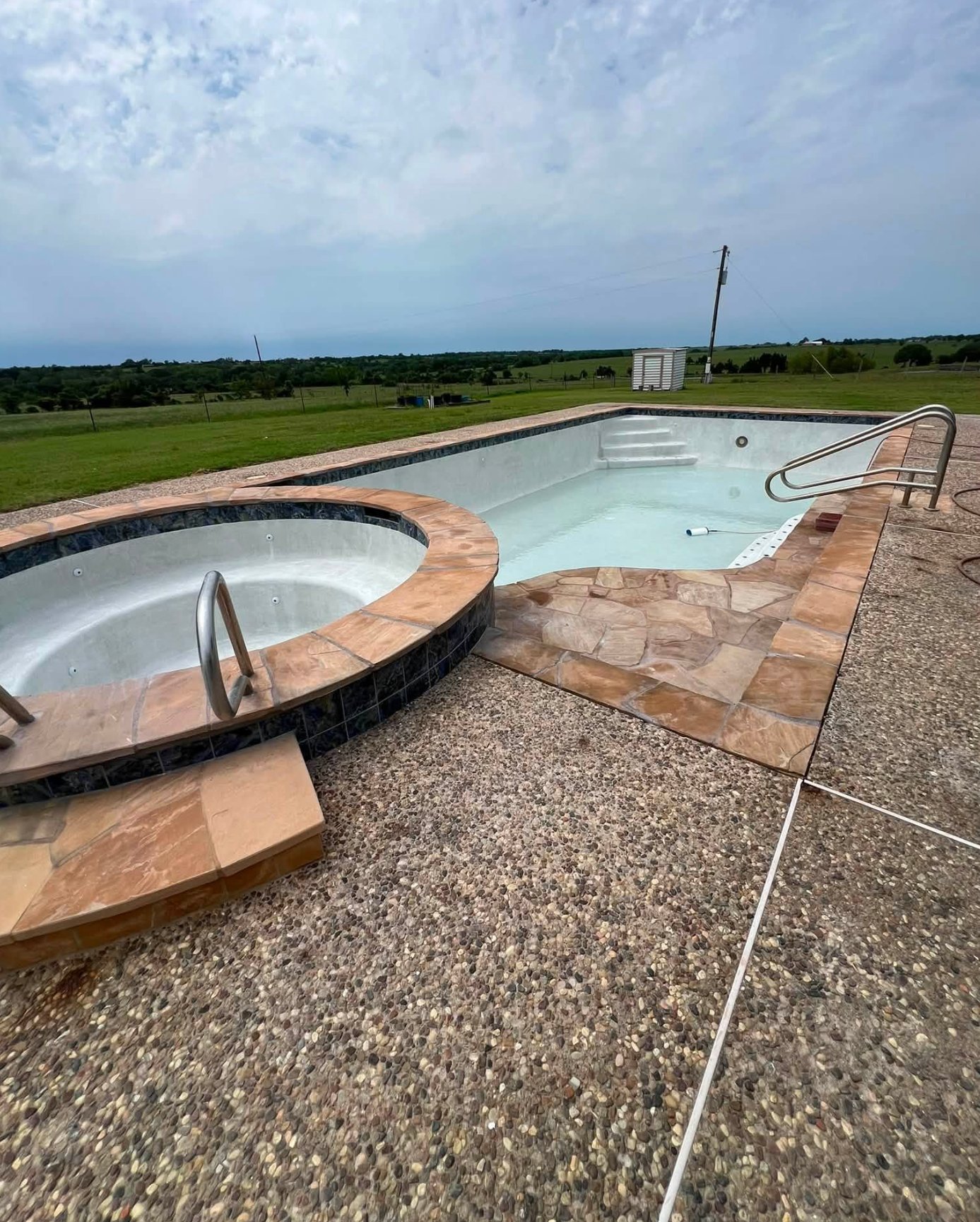 Pool deck before resurfacing, showing worn exposed aggregate concrete