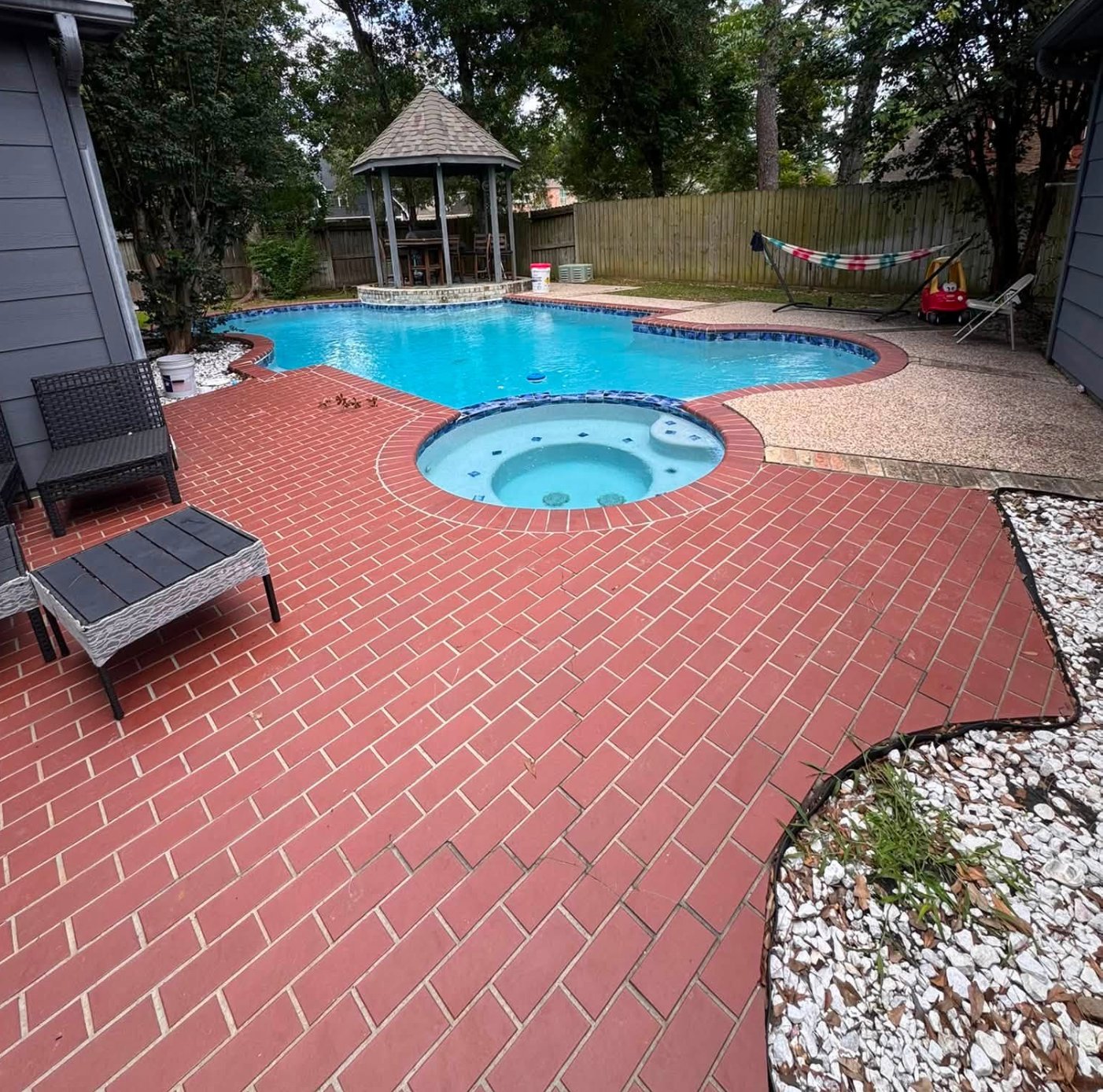 Pool deck before renovation, showing worn red brick pavers with gazebo in background