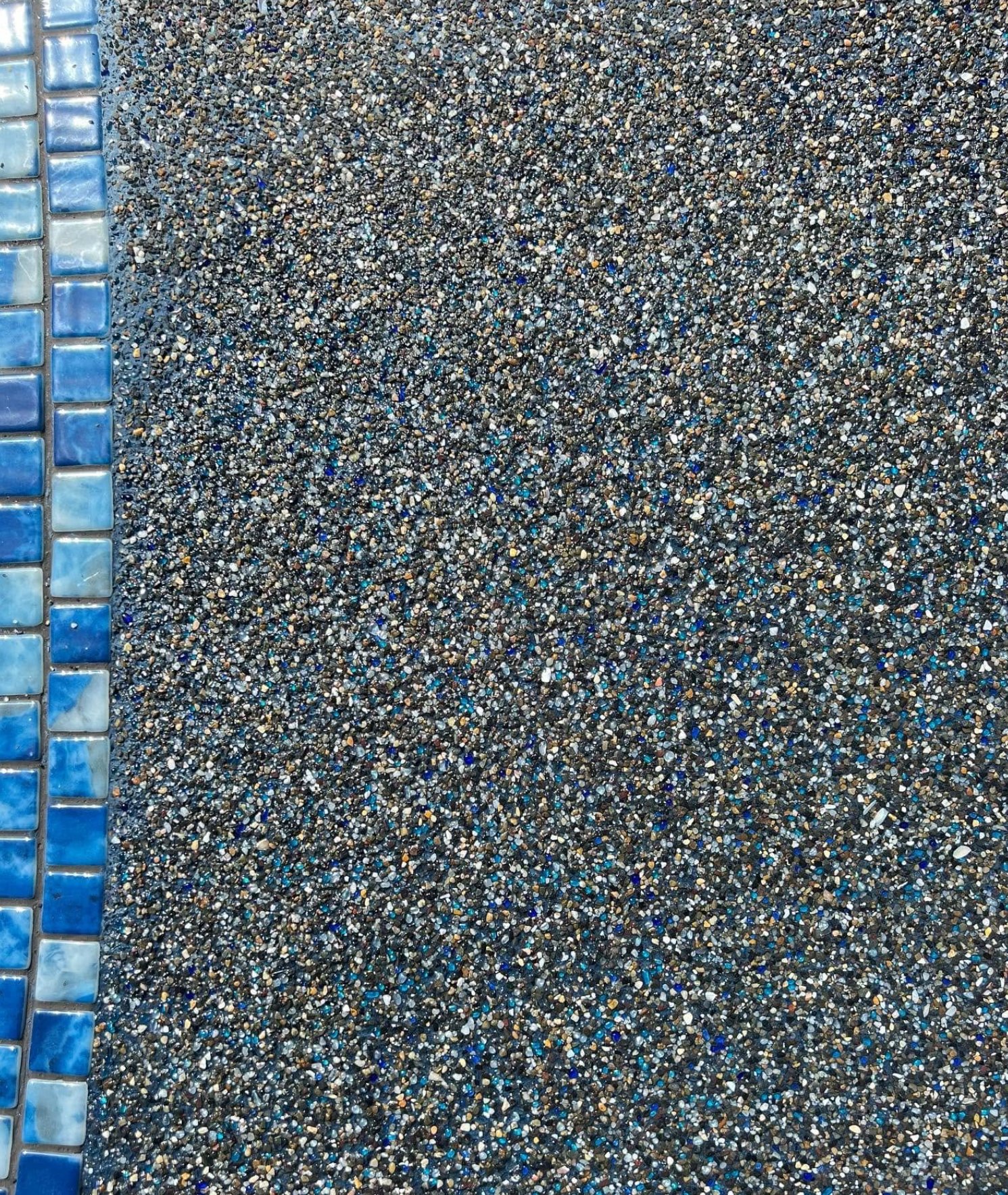 Close-up of PebbleTec pool finish texture along the waterline tile