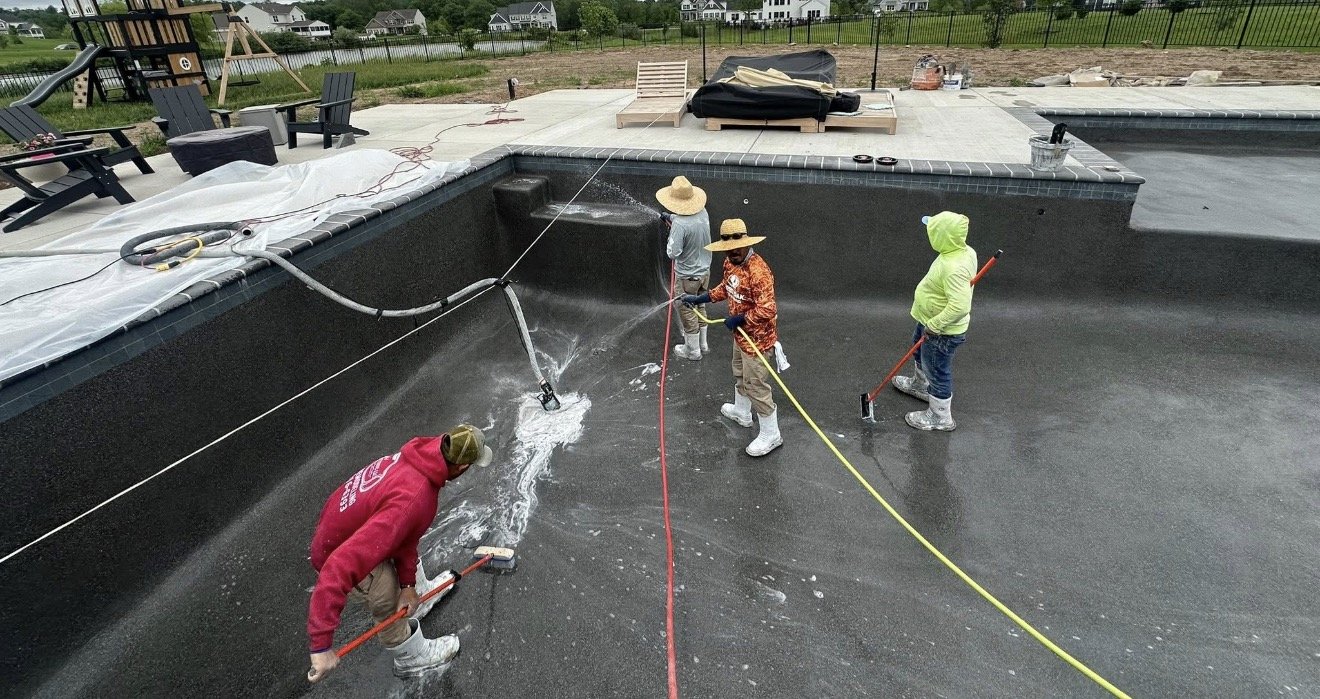 Crew applying fresh plaster finish to a drained pool during resurfacing