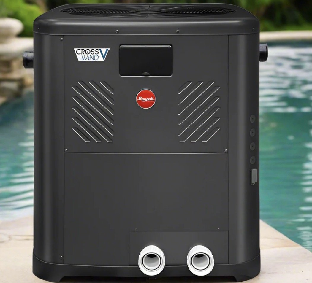 Raypak Crosswind V pool heat pump on site before installation next to a backyard pool